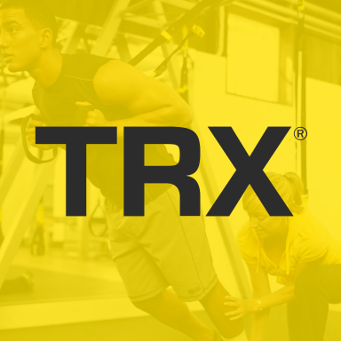 A person using TRX equipment with a trainer offering assistance.